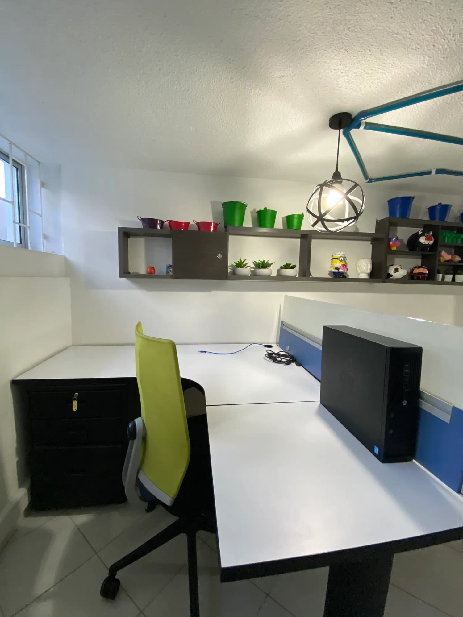 Escritorio dedicado en L con silla verde y repisa decorada