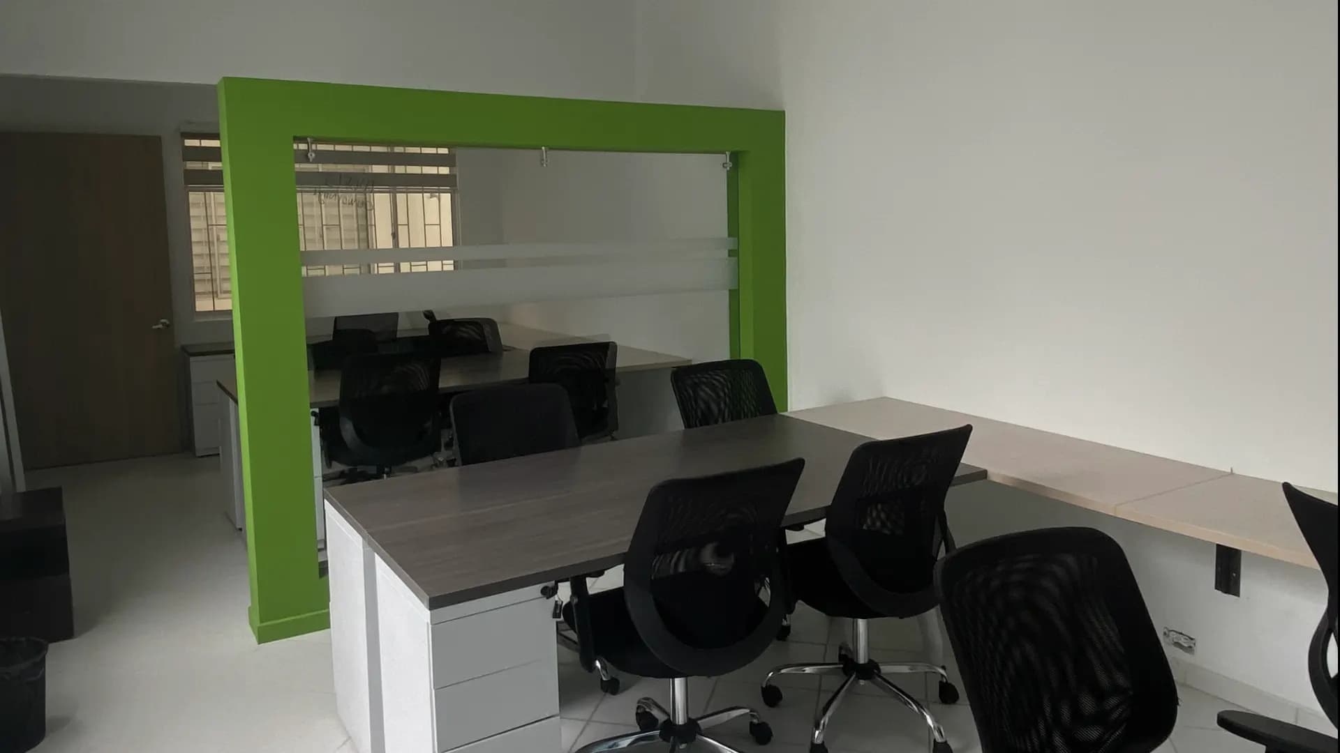 Oficina privada con escritorios y marco verde de vidrio